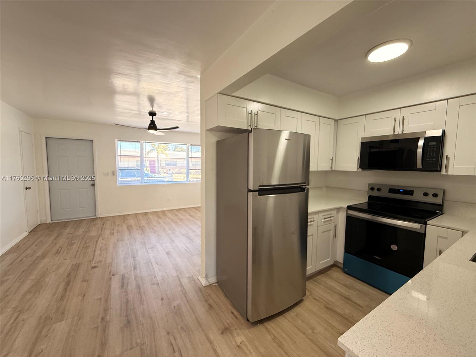 801 Southwest 7th Street, Unit B Pompano Beach, FL 33060 - Photo 2 of 20 a kitchen with a refrigerator a stove top oven and wooden floor