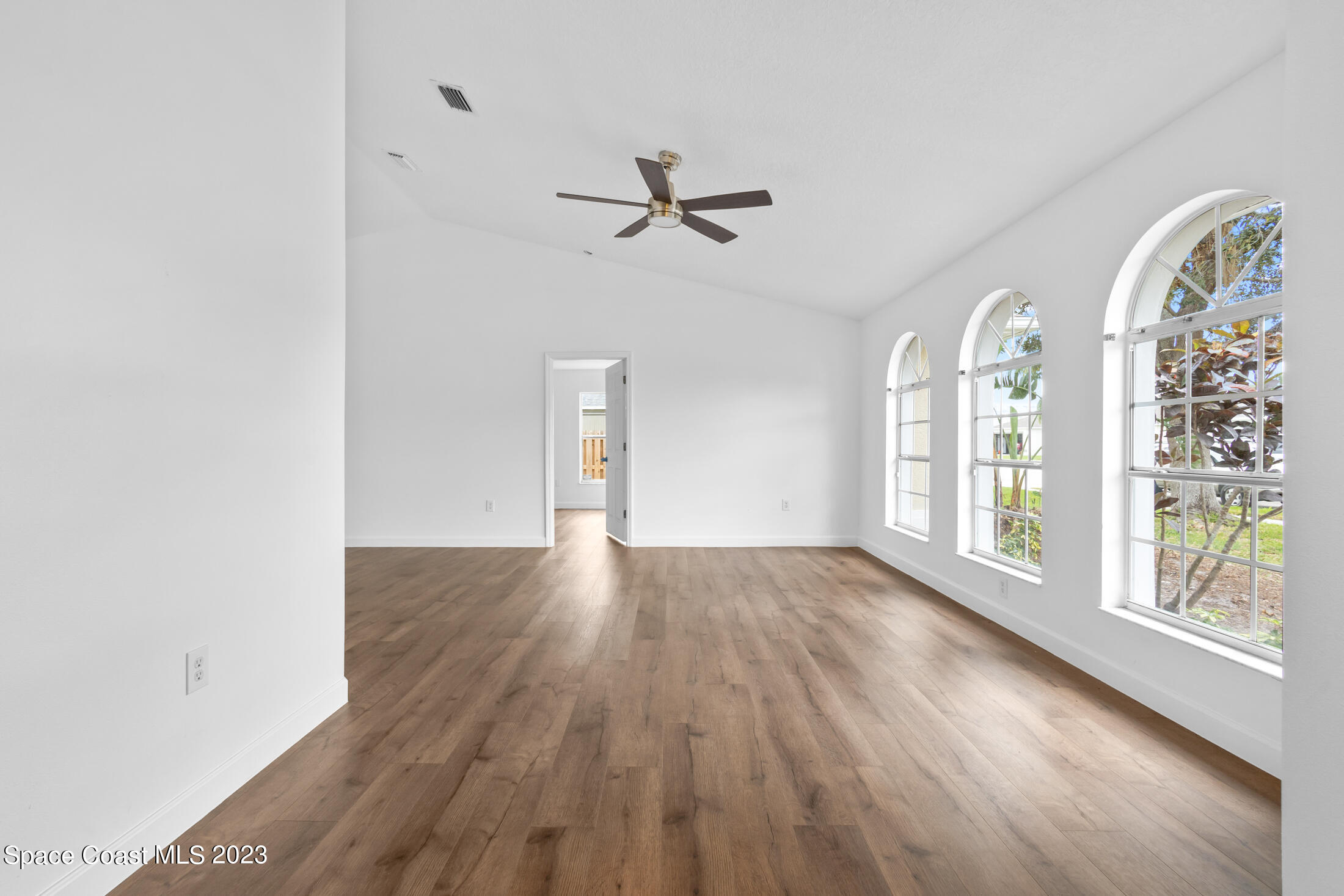 1940 Slone Boulevard Melbourne, FL 32935 - Photo 4 of 27 an empty room with wooden floor fan and windows