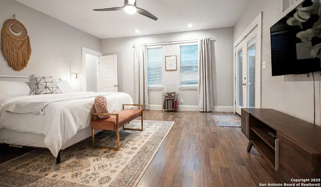 a bedroom with a bed wooden floor and a flat tv screen