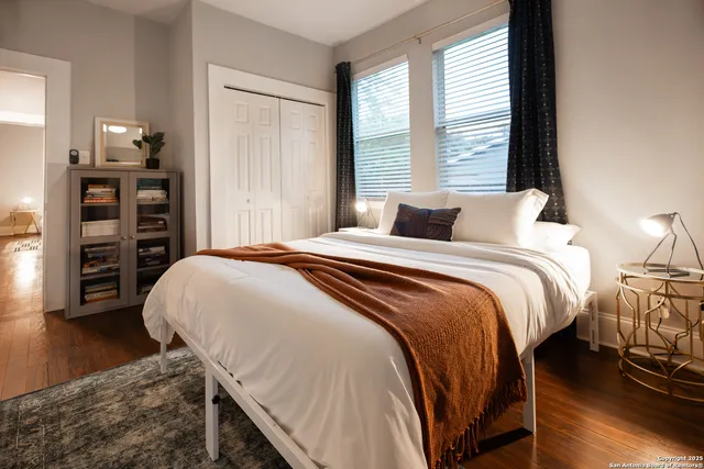 a bedroom with a bed a dresser and a large window