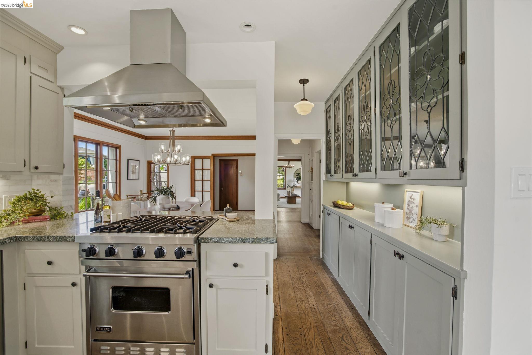 1087 Hubert Road Oakland, CA 94610 - Photo 13 of 67 Gourmet kitchen featuring a stainless steel range with a matching vent hood, light granite countertops, a subway tile backsplash, and extensive custom cabinetry with leaded glass uppers