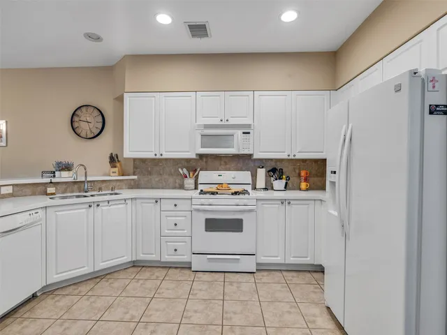 a kitchen with white cabinets and white appliances
