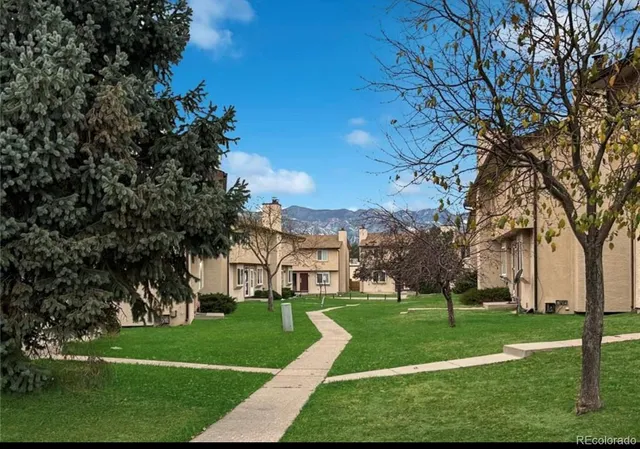 a view of a white house with a big yard and large trees