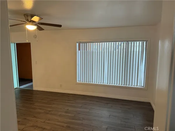 an empty room with wooden floor fan and windows