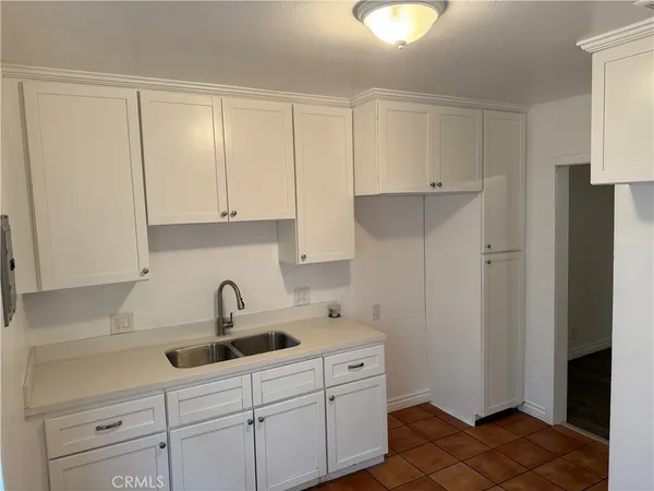 a kitchen with white cabinets and sink
