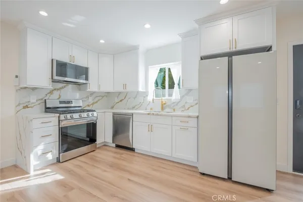 a kitchen with white cabinets and appliances