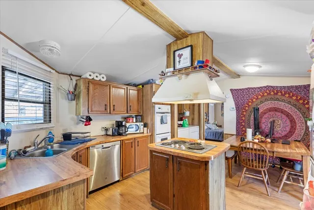 a kitchen with stainless steel appliances a stove a sink dishwasher and white cabinets with wooden floor