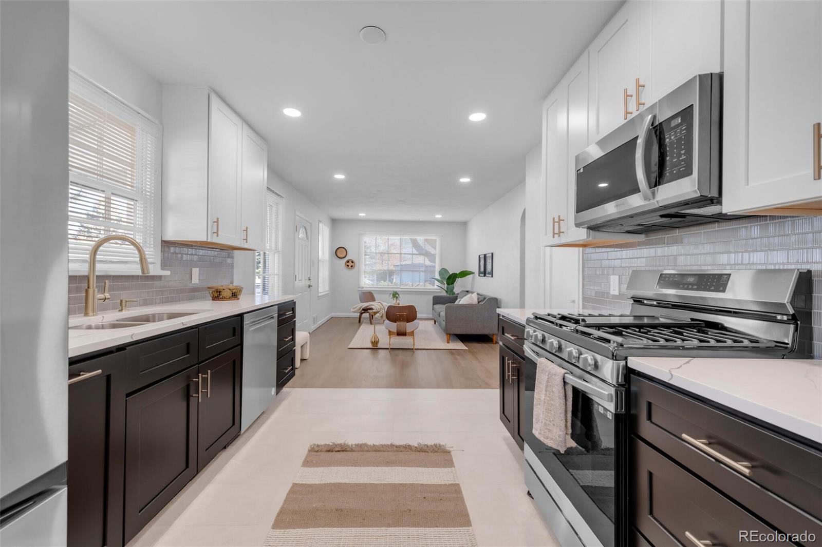 a open kitchen with stainless steel appliances granite countertop a stove top oven a sink dishwasher and a microwave oven with large wooden cabinets