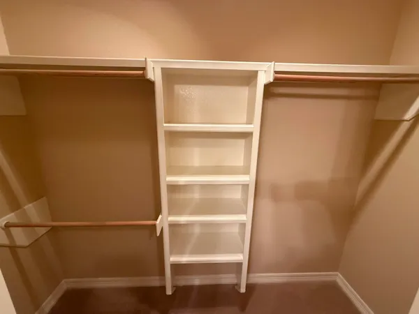 a view of walk in closet with empty racks