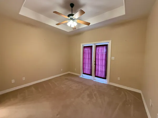 an empty room with windows and fan