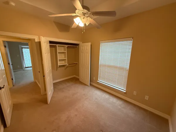 an empty room with closet and a ceiling fan