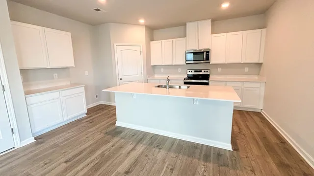 a large kitchen with cabinets wooden floor and stainless steel appliances