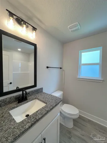 a bathroom with a granite countertop sink a toilet and a mirror