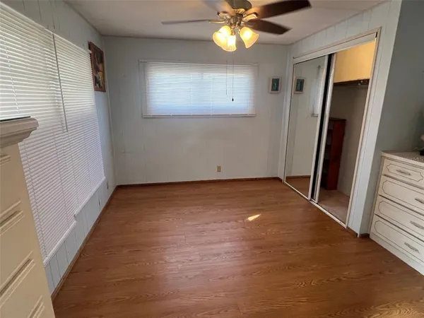 an empty room with wooden floor and fan