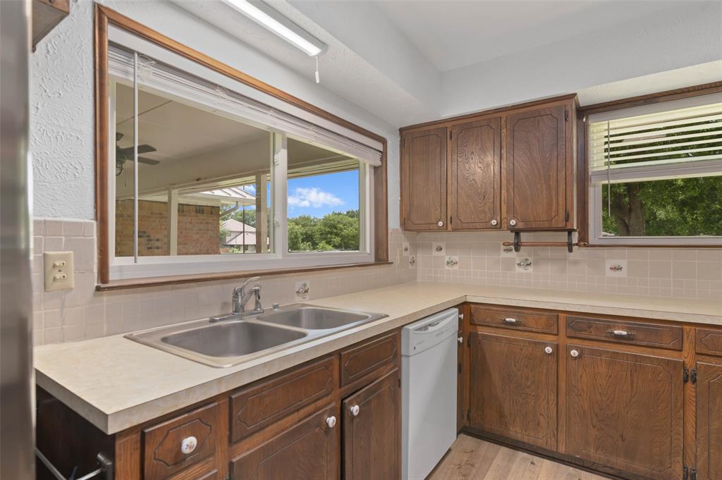 301 East 6th Street Krum, TX 76249 - Photo 14 of 29 Kitchen featuring wood-finish cabinetry, solid surface countertops, and large windows allowing in plenty of natural light.