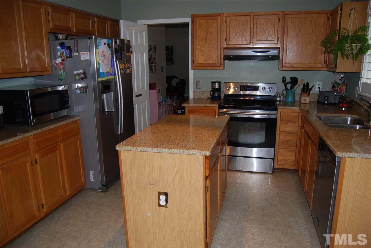 12301 Inglehurst Drive Raleigh, NC 27613 - Photo 11 of 23 a kitchen with a refrigerator a stove and wooden cabinets