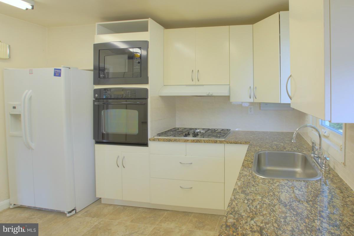 7514 Labyrinth Road Baltimore, MD 21208 - Photo 11 of 27 a kitchen with a refrigerator sink stove and cabinets