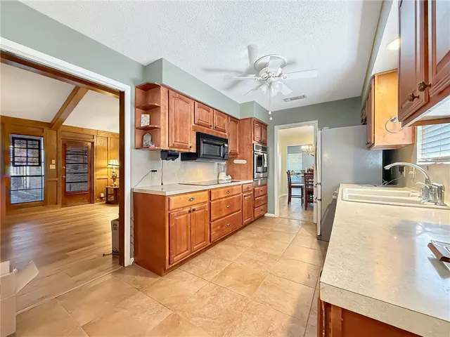 a kitchen with stainless steel appliances granite countertop a sink counter space cabinets and a stove top oven