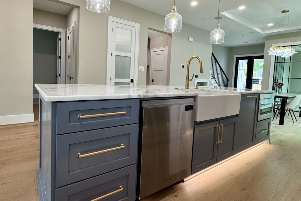 3100 Garwood Street Austin, TX 78702 - Photo 10 of 25 Kitchen island featuring a white marble countertop, a farmhouse sink with a gold-toned faucet, and dark blue cabinetry with gold-toned hardware