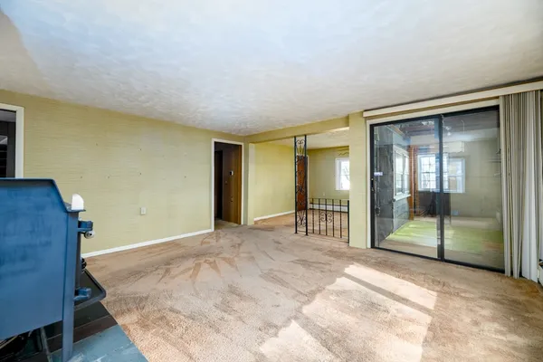 a view of an empty room with wooden floor and a bathroom