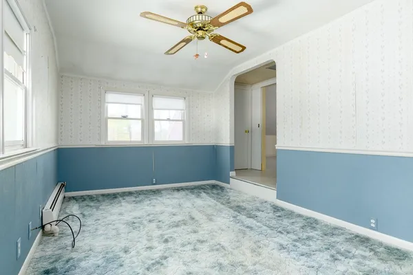 an empty room with windows and fan