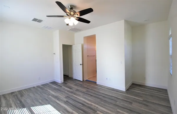 an empty room with wooden floor and a ceiling fan
