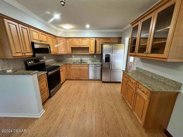 a kitchen with stainless steel appliances granite countertop wooden cabinets a refrigerator a stove a sink and a microwave