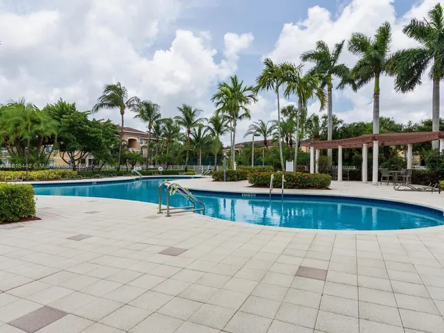 a view of swimming pool with seating space and trees in the background