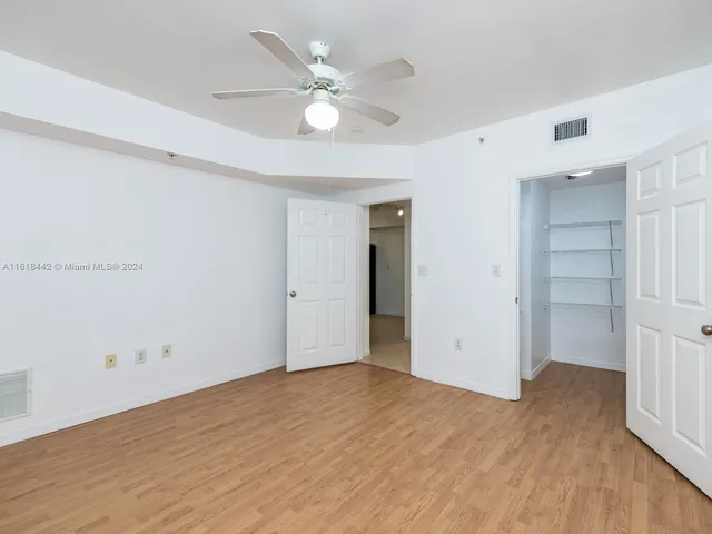 an empty room with wooden floor and ceiling fan