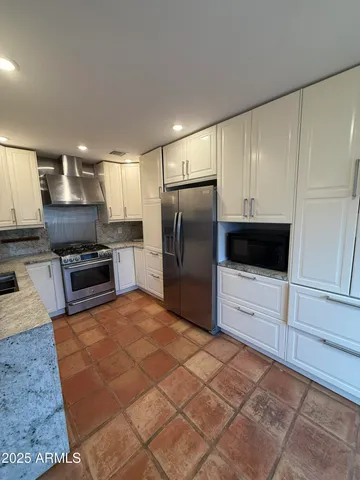 a kitchen with granite countertop a refrigerator and a stove top oven