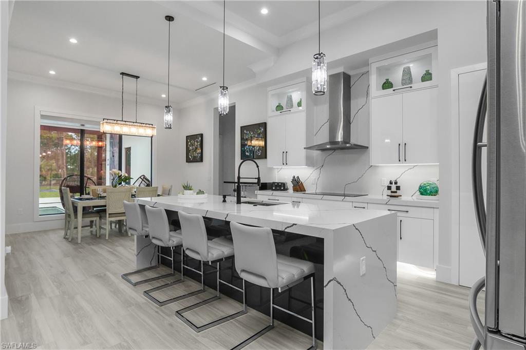1347 23rd Street Southwest Naples, FL 34117 - Photo 24 of 50 a kitchen with a dining table chairs a sink dishwasher a refrigerator and cabinets