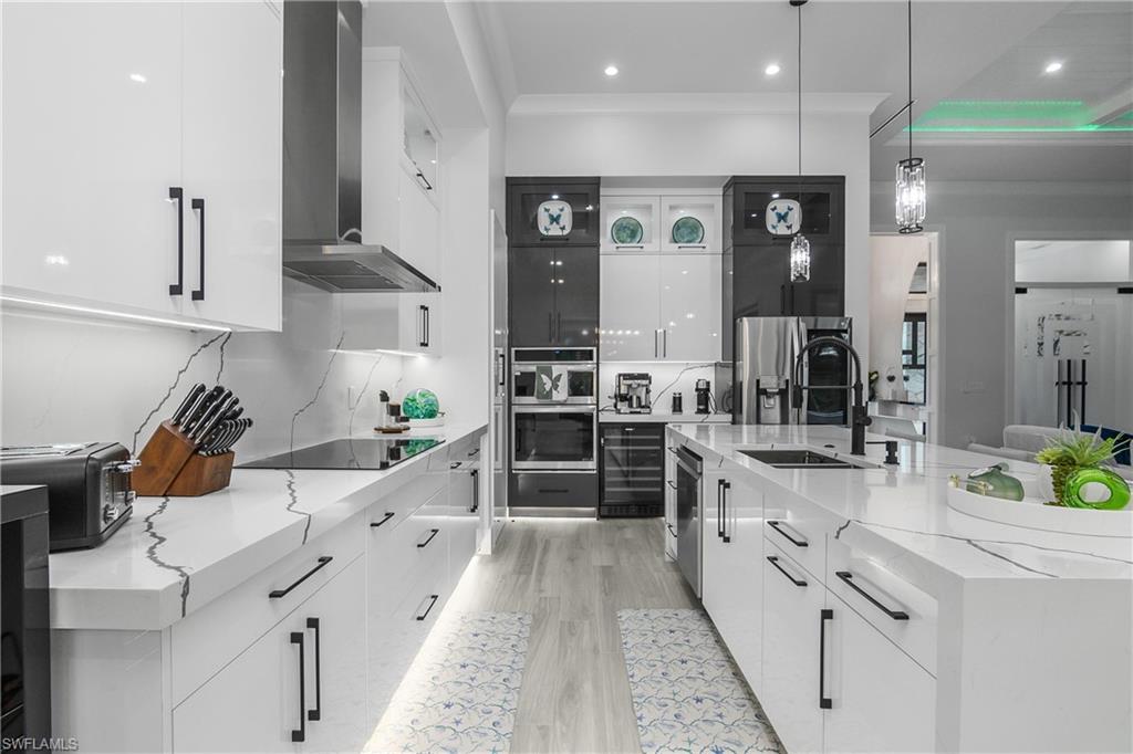 1347 23rd Street Southwest Naples, FL 34117 - Photo 27 of 50 a large white kitchen with stainless steel appliances kitchen island granite countertop a lot of counter space and a sink