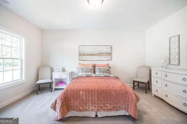 a bedroom with a bed chair and two windows