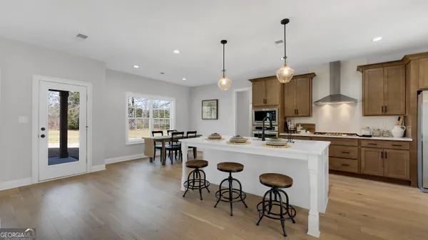 a kitchen with kitchen island a dining table chairs stainless steel appliances and cabinets