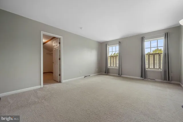 a view of an empty room with window and bathroom
