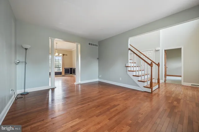 a view of an empty room with wooden floor and a bathroom