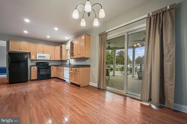 a kitchen with stainless steel appliances granite countertop a refrigerator a sink dishwasher and a stove with wooden floor