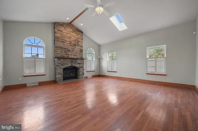 an empty room with windows fireplace and wooden floor