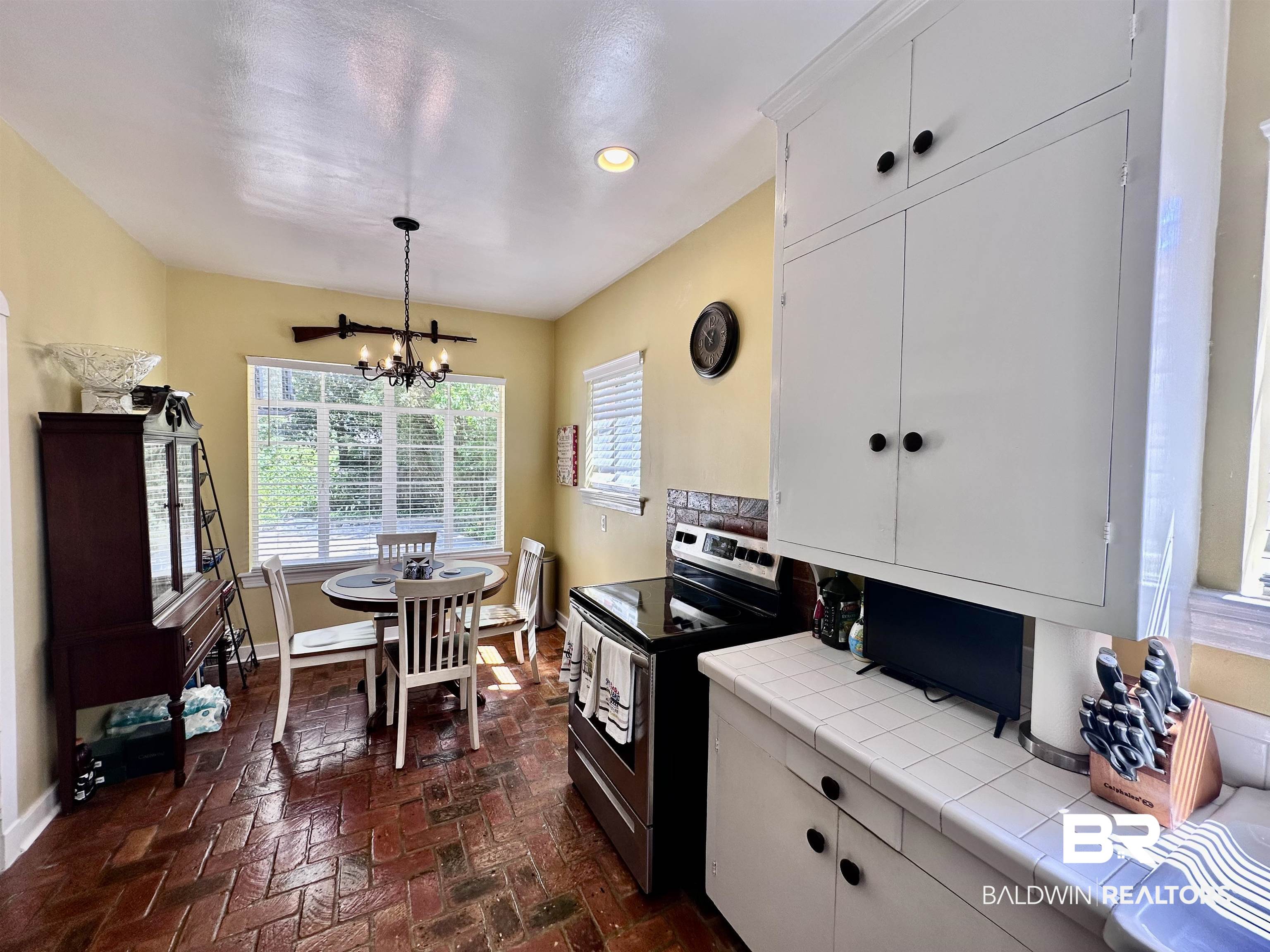 260 Siena Vista Street Mobile, AL 36607 - Photo 18 of 41 Kitchen featuring tile countertops, stainless steel range with electric stovetop, baseboards, a chandelier, and brick flooring