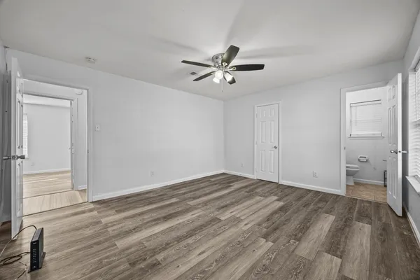 a view of empty room with wooden floor and fan