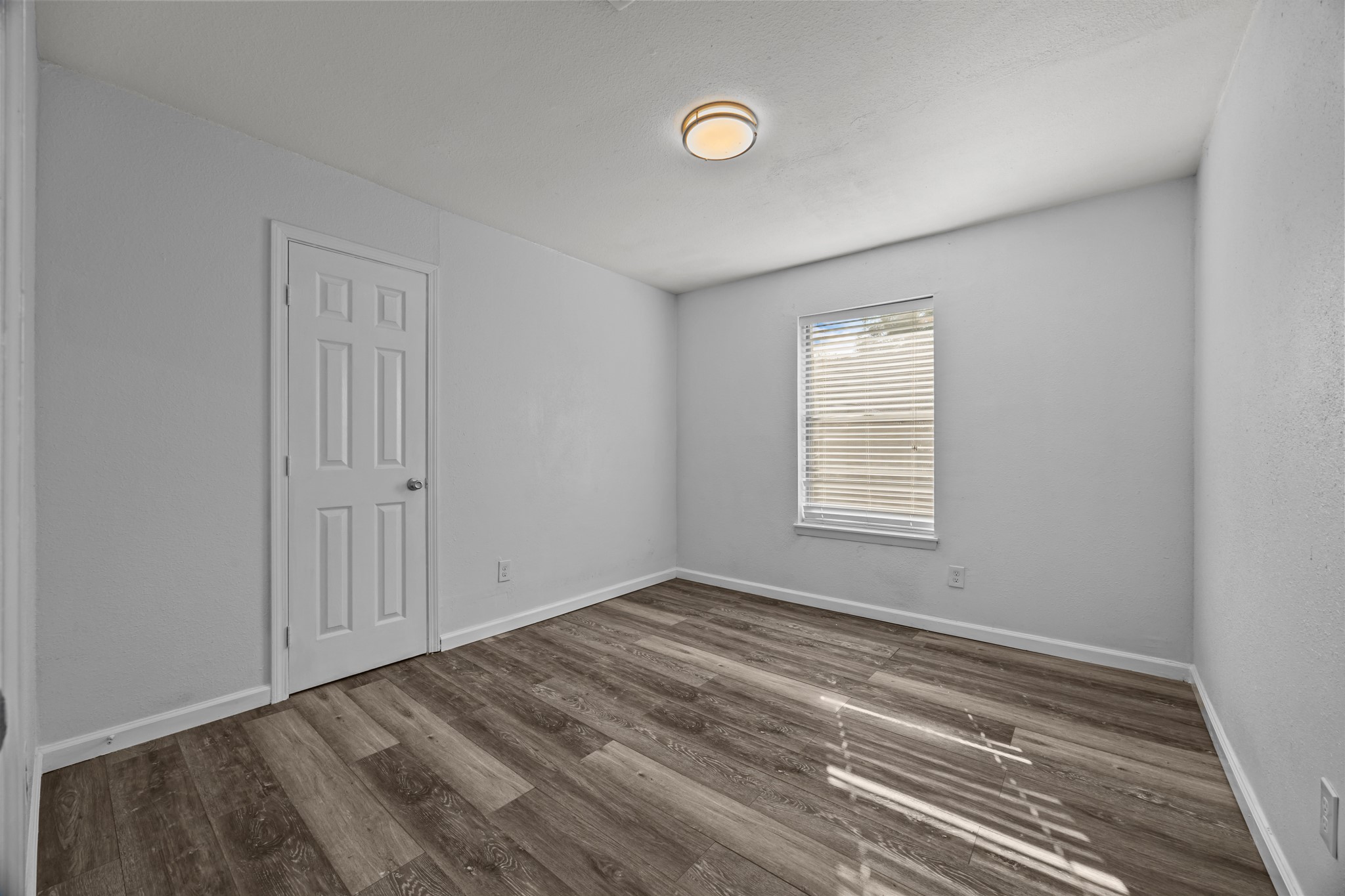 2103 6th Street Stafford, TX 77477 - Photo 17 of 27 a view of an empty room with wooden floor and a window