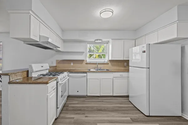 a kitchen with stainless steel appliances granite countertop a refrigerator sink and white cabinets