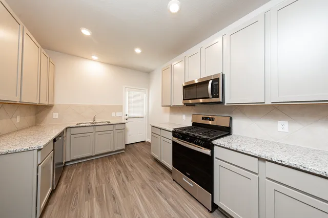 a kitchen with a sink stove top oven and cabinets