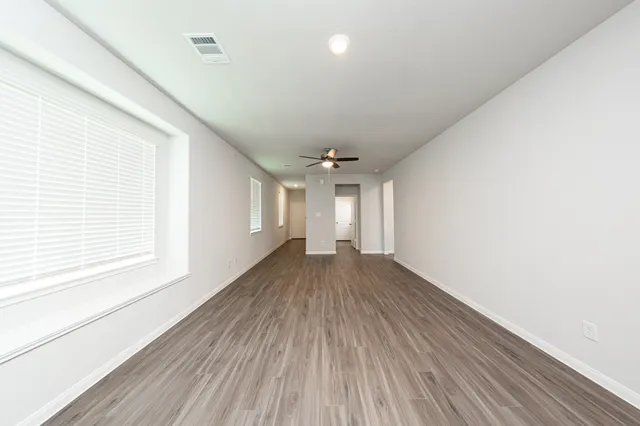 a view of empty room with wooden floor and fan