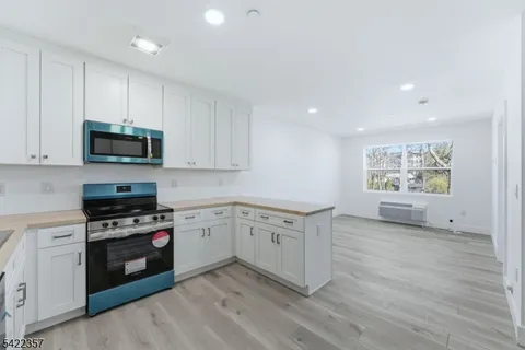 a kitchen with granite countertop a stove top oven cabinets and a wooden floor