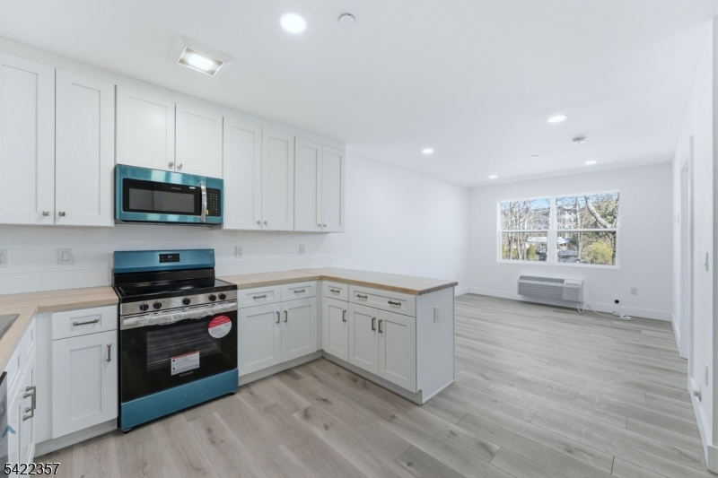 a kitchen with granite countertop a stove top oven cabinets and a wooden floor