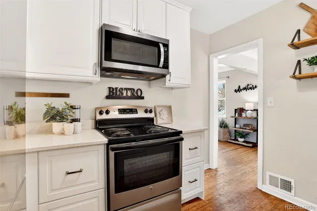 a kitchen with cabinets stainless steel appliances and wooden floor