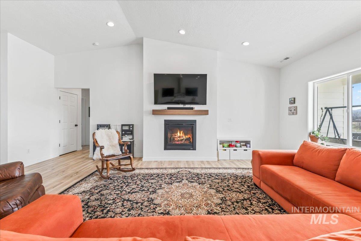 8843 Highway 78 Marsing, ID 83639 - Photo 13 of 48 Living room with vaulted ceiling, a glass covered fireplace, light wood-type flooring, and recessed lighting