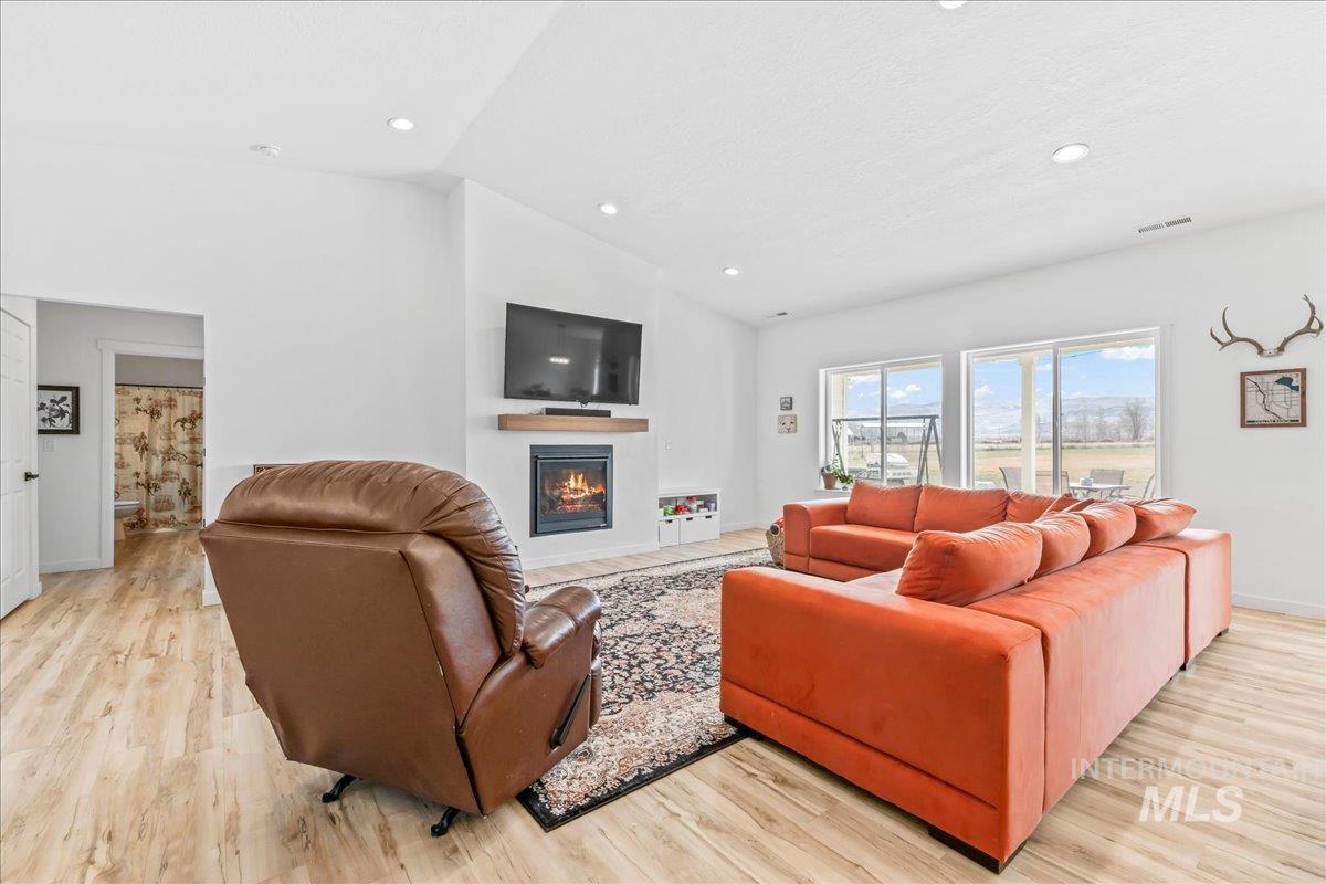 8843 Highway 78 Marsing, ID 83639 - Photo 15 of 48 Living room with a glass covered fireplace, vaulted ceiling, light wood-style floors, and recessed lighting