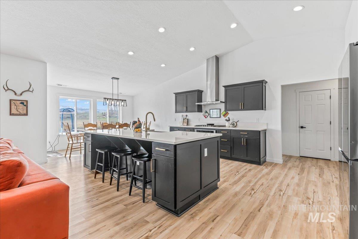 8843 Highway 78 Marsing, ID 83639 - Photo 17 of 48 Kitchen with a breakfast bar area, lofted ceiling, light wood finished floors, a kitchen island with sink, and light stone countertops